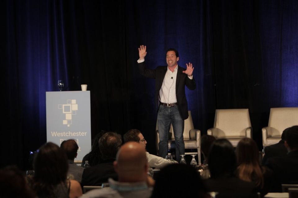 Chris Dessi on stage hosting a summit